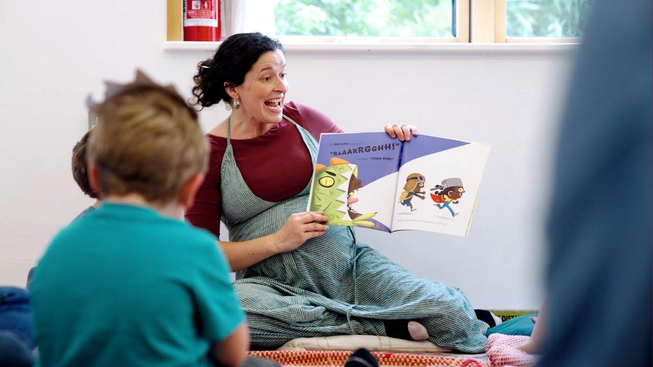 A Fair Tales reading session: a woman reads a monster picture-book aloud to young children.