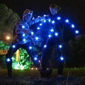 Night shot at Green Man Festival: two people wearing 'neuron suits' — dark outfits strung with bright blue LED nodes.