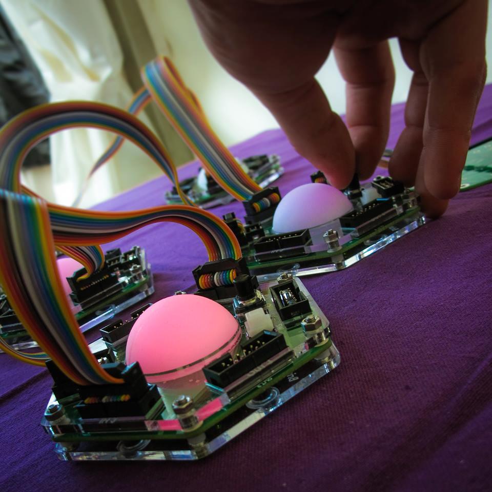 Close-up of Tangible Networks nodes: hexagonal acrylic units with glowing domes joined by ribbon cables.